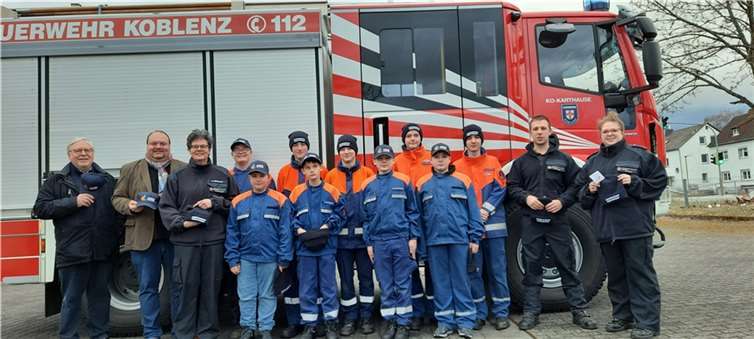 V.l.: Michael Gross und Thorsten Schneider übergeben Kappen und Mützen an die Burschen der Karthäuser Jugendfeuerwehr.  Foto: privat