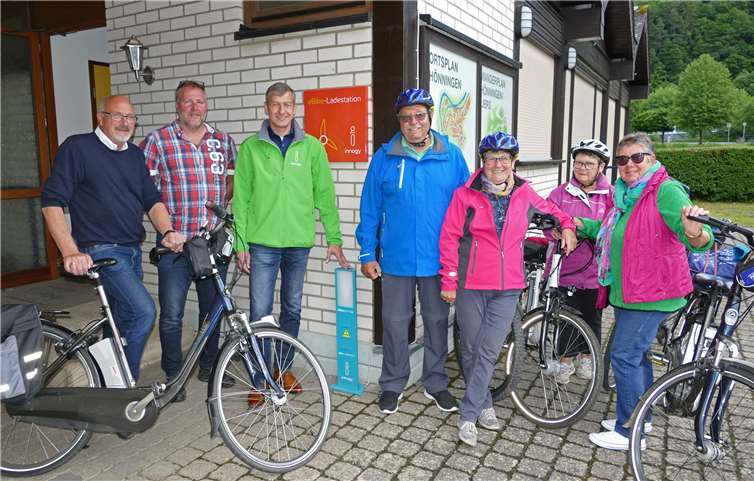 (V.li.n.re.) Jürgen Schwarzmann, erster Beigeordneter der Ortsgemeinde Hönningen, Ralf Minwegen, zweiter Beigeordneter der Ortsgemeinde, Michael Dötsch, Kommunalbetreuer bei innogy, sowie Radfahrer und Radfahrerinnen aus Hönningen nahmen die neue E-Bike-Ladestation am Gemeindehaus in Liers offiziell in Betrieb. Foto: privat