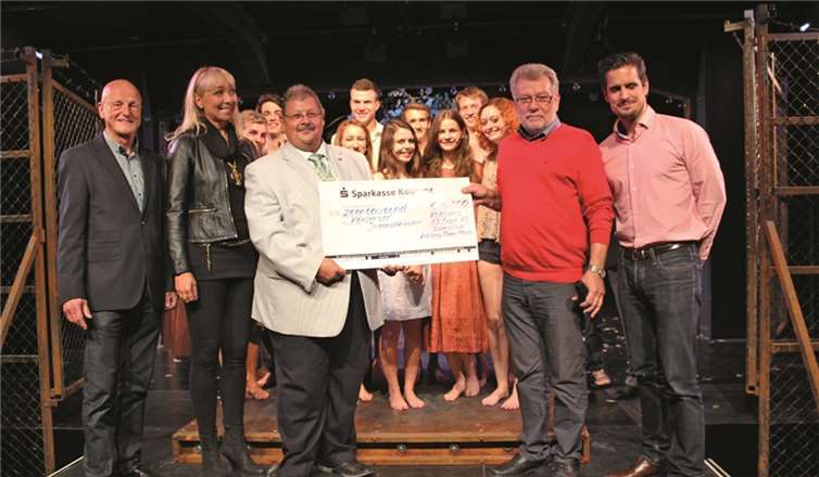 V.l.n.r.: Rainer Vogel (Mentor des Lionsclubs Koblenz-Rhein/Mosel für das Jugendtheater), Christiane Ebeling (Ex-Confluentia, Lionsclub Sophie von La Roche Koblenz), Dieter Balter (Präsident Lionsclub Koblenz-Rhein/Mosel), Werner Schaab und Christian Altmaier (Jugendtheater Koblenz) sowie im Hintergrund das gesamte Theaterensemble bei der Scheckübergabe.privat