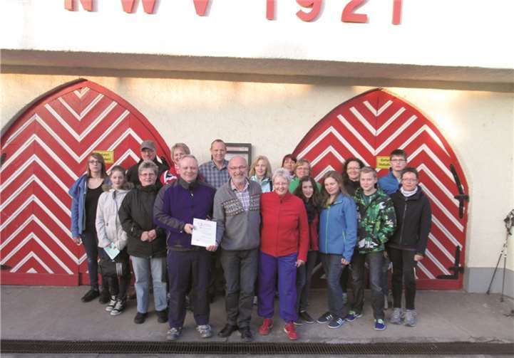 Volker Strohe (vorne links), Michael Weber (Präsident des Kanuverbandes, vorne Mitte) und Jürgen Straub (Kanurennsportwart beim Verband Rheinland, hinten Mitte) am Bootshaus an der Rheinbrücke mit einem Teil der Kanumannschaft, Nordicwalking Gruppe sowie Vorstandsmitglieder (im Hintergrund).Privat