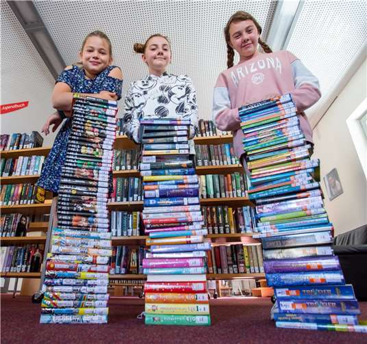 Von links: Hannah Schnug, Julina und Michelle Lorraine verschlagen stapelweise Bücher im Lesesommer der Stadtbücherei Selters. Foto: Stadt Selters