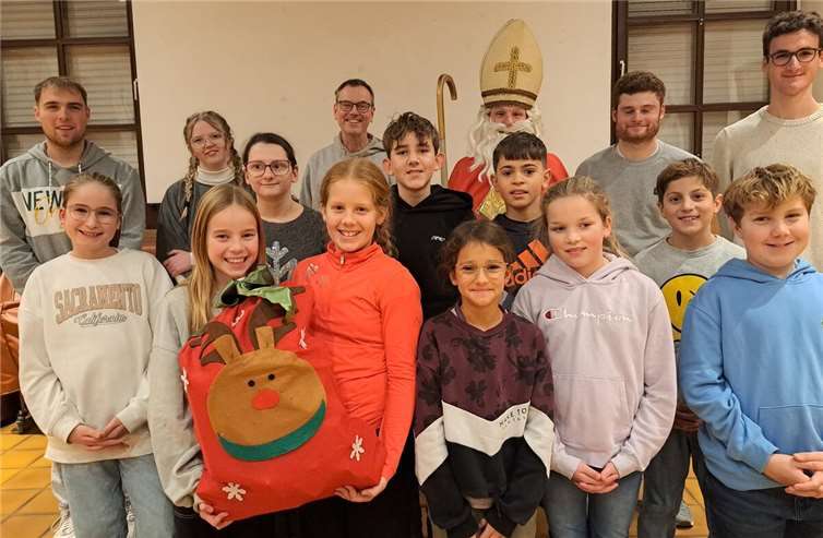 Von links nach rechts, vordere Reihe: Marlene Nonn, Anni Boos, Malina Meid, Leandra Bonn, Adrian Neumann, Mona und Kilian Hilger, Emma Wohde, Moritz Witte und Moritz Sieben, und hintere Reihe Lukas Lindemann, Leonie Beißel, Pastor Norbert Missong, der heilige Nikolaus, Raphael Weber und Leonard Schütz. Foto: Monika Bermel