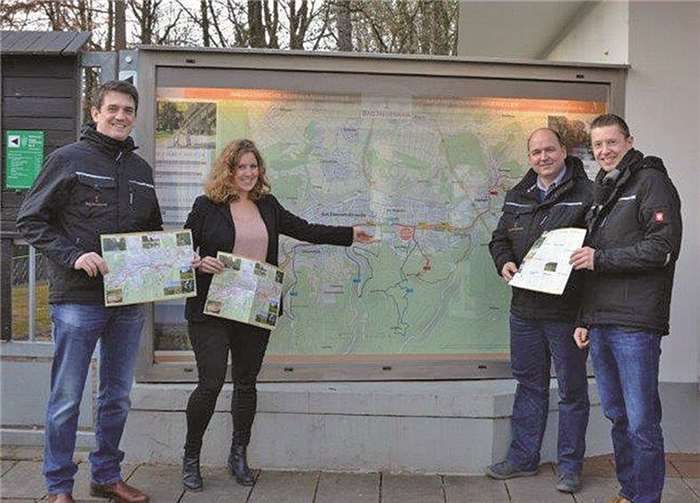 Von rechts Geschäftsführer Christian Senk, Markus Bauer, Sabrina Heine und Jan Ritter präsentieren die neuen Faltpläne sowie die große Wanderkarte neben dem Service-Center der Heilbad-Gesellschaft. privat
