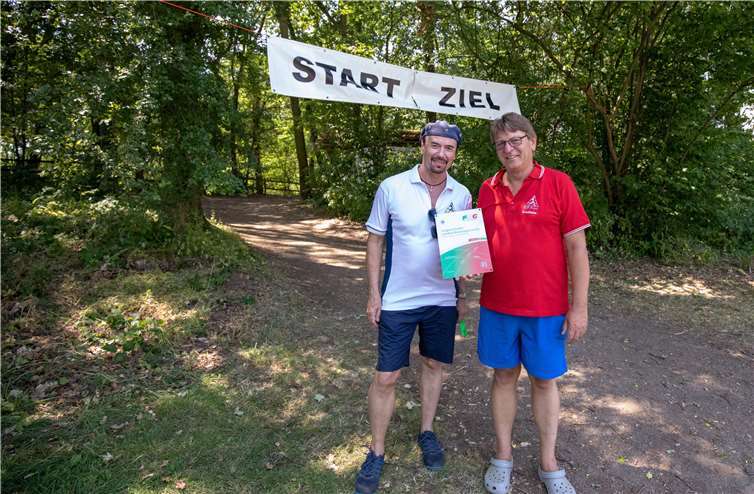 Vor der Start- und Zielliinie für das Crossrunning zeigen der Vorsitzende Friedhelm Trinkl und Schatzmeister Dieter Klein die Auszeichnung des Familiensportbunds.