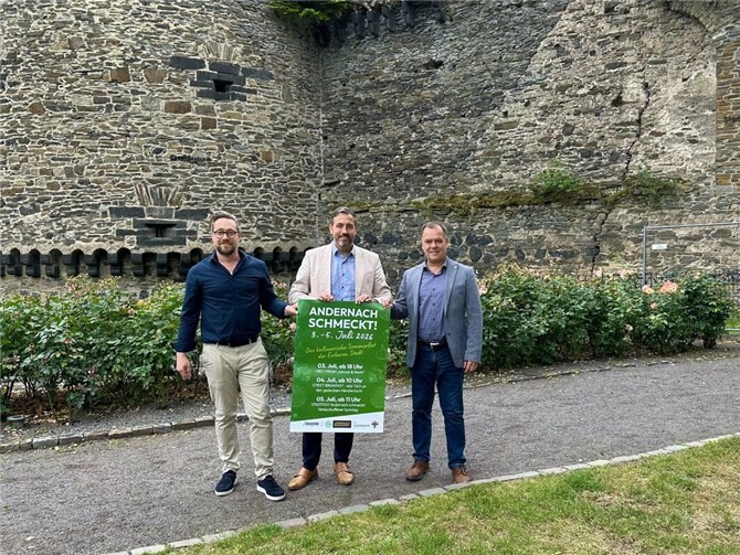 „Vorfreude auf das kulinarische Sommerfest: (v.l.) Johannes Lewenberg (Stadtmarketing), Oberbürgermeister Christian Greiner und Thomas Münzer (Perspektive gGmbH) präsentieren im Andernacher Schlossgarten das Plakat zum Highlight-Wochenende „Andernach schmeckt!“.  Foto: Stadt Andernach/Neele Kremer“