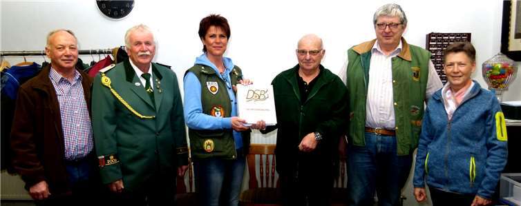 Vorstandsmitglieder begleiten Hans Joachim Bürschgens, der nach jahrzehntelanger Begleitung des Vorstandspostens als Sportwart symbolisch die Sportordnung des Rheinischen Schützenbundes an seine Nachfolgerin Michaela Gröff weiterreicht. (Bildmitte, weitere v. li.: Martin Eder, Waffenreferent, Gerhard Lerch, 1. Vorsitzender, Hans Werner Reiser, Geschäftsführer und Kassenwart, Marga Eder, Damenwartin).Foto: Ulli Burkholz