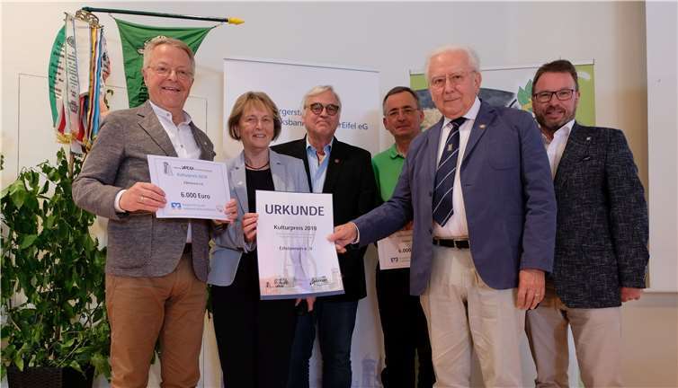 Vorstandsvorsitzender Elmar Schmitz von der Volksbank RheinAhrEifel (links) sowie Albert Nell, Vorstandsvorsitzender der Stiftung LAPIDEA für Kunst und Kultur (rechts vorne) überreichen Mathilde Weinandy in ihrer Funktion als (Noch-) Hauptvorsitzende des Eifelvereins den Kulturpreis 2019. Fotos: Norgart Gudat
