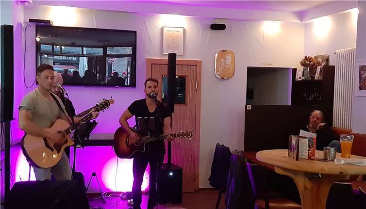 Während der Vernissage am Freitag: Die Musiker Coral, Thomas undPhilip von The Acoustics - rechts am Tisch lauschend der Künstler Boogie Chillun.