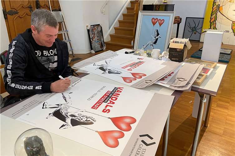 Während eines Besuchs in der STADTGALERIE Mennonitenkirche signiert JPS einige Ausstellungsplakate, die sein „Don’t Look Back in Anger“ zeigen.  Foto: Stadt Neuwied / Melanie Lange