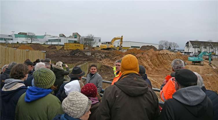 Während im Hintergrund die Bagger den Erdaushub forcieren, informieren Bürgermeister Holger Jung und der Leiter des städtischen Gebäudemanagements Andreas Satzer (beide Mitte) die interessierten Bürgerinnen und Bürger über die Baufortschritte. Foto: Stadt Meckenheim