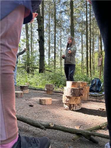 Waldpädagogin Kristin Reitz erklärt den Kindern die Station „Wald für Generationen“.