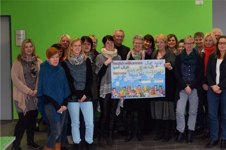 Waltraud Frick-Lorenz (Mitte, hinter dem Plakat) und der 1. Kreisbeigeordnete Achim Hallerbach empfingen 25 pädagogische Fachkräfte zur Fortbildung zum Thema kultursensible Pädagogik.Kreisverwaltung