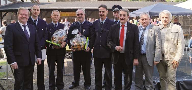 Wehrführer Thomas Christmann (Mitte) und Hans-Albert Henneberger bekamen zum Dank neben den Urkunden auch einen Präsentkorb von ihren Kameraden überreicht. Erik Nagtzaan (5.v.re.) und Alexander Blatt (2.v.li.) sind ihre Nachfolger.