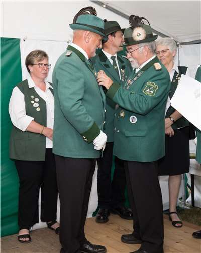 Wilhelm Ippendorf verleiht dem neuen Schützenkönig das Ehrenabzeichen.