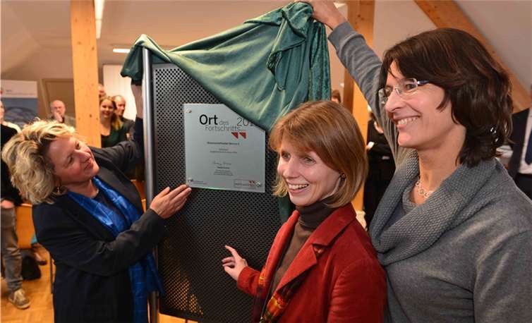 Wissenschaftsministerin Svenja Schulze, Dr. Anke Valentin und Brigitte Peter (Geschäftsführerinnen des WILA Bonn e.V.) enthüllen das Auszeichnungsschild „Ort des Fortschritts“ (v.l.).Norbert Steinhaus