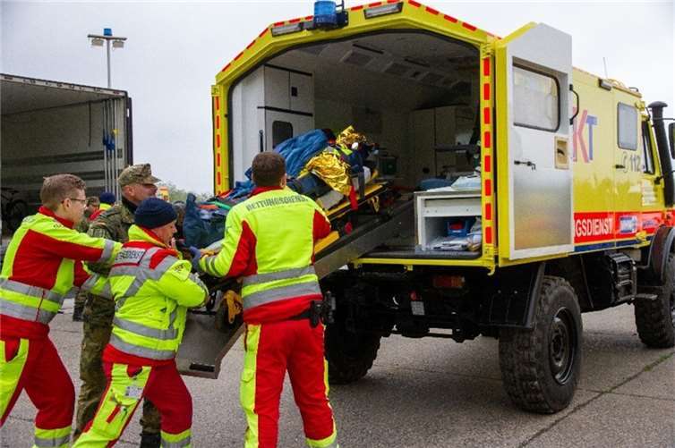 Zivil-militärische Rettungskräfte trainieren das Beladen eines Rettungsfahrzeugs.