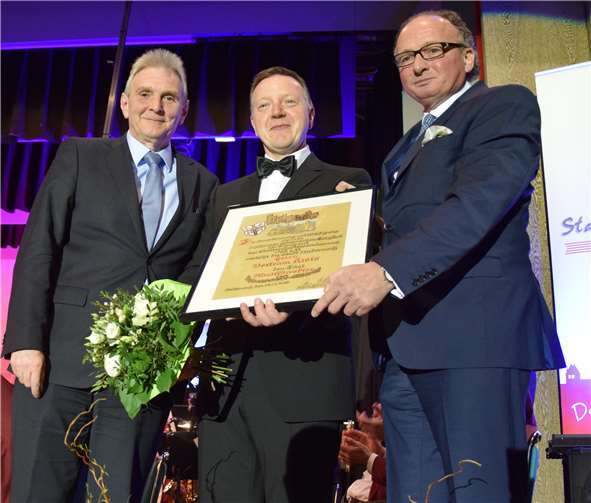 Zum 25-jährigen Jubiläum überreichten Oberbürgermeister Achim Hütten (rechts) und Bürgermeister Claus Peitz (links), Stadtkapellmeister Bertram Kleis eine Urkunde und beförderten ihn zum Musikdirektor.