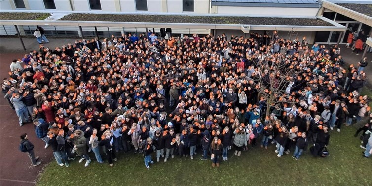 Zum Abschluss des Projekt versammelte sich die Schulgemeinschaft auf dem Schulhof um mit orangen Handschuhen ein weiteres Zeichen für eine positive und gewaltfreie Zukunft zu setzen. Foto: Christian Fenioux