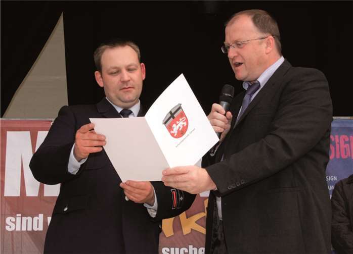 Zum Jubiläum der Feuerwehr überreicht Bürgermeister Guido Nisius eine Dankurkunde an Wehrführer Sebastian Heinrich. -SES-