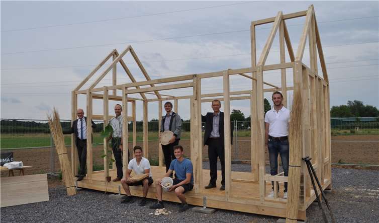 Zusammen mit Wirtschaftsförderer Dirk Schwindenhammer (4.v.l.) verschaffte sich Bürgermeister Bert Spilles (links) einen Eindruck von dem Demonstrationsgebäude, welches Raphael Reichert und Julian Weber (sitzend von links) errichten. Prof. Dr. Ralf Pude (2.v.l.) und Prof. Dr. Mathias Wirths (3.v.l.) begleiten die beiden Studierenden bei der Umsetzung ebenso wie der Wissenschaftliche Mitarbeiter Jano Knopp (rechts). Foto: Stadt Meckenheim