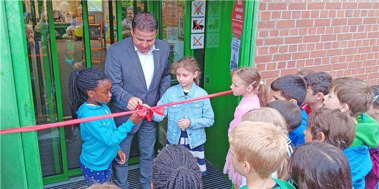 Zusammen mit den Grundschülerinnen Getey und Sophia löste Bürgermeister Holger Jung das rote Band am Eingang der Meckenheimer Bücherei. Foto: Stadt Meckenheim