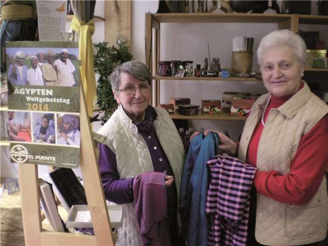 Zwei Mitarbeiterinnen des Ladenteams präsentieren einige Schals. Mit ihrem Verkauf wird den Weberinnen ein bescheidenes Einkommen ermöglicht. privat