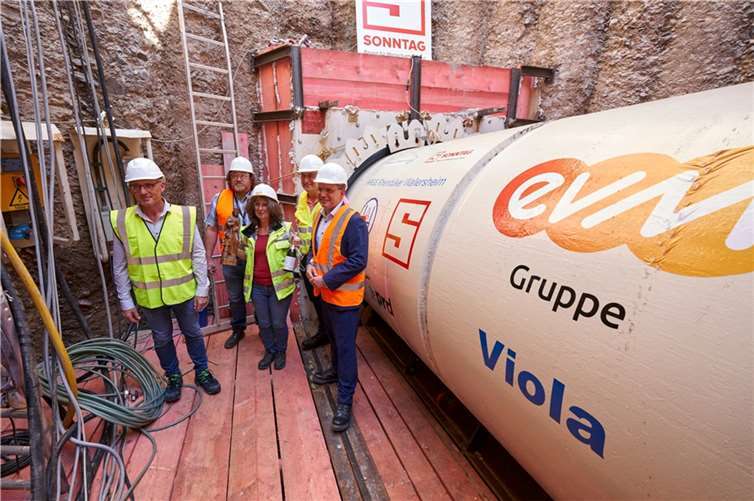 evm-Vorstandsvorsitzender Josef Rönz, Wolfgang Kochhan, Leiter Wasserwirtschaft bei der evm, Taufpatin Viola Pöllmann-Kux, Ortsbürgermeister Horst Klöckner und VWM-Geschäftsführer Lars Hörnig in der zwölf Meter tiefen Baugrube vor dem Bohrkopf, der den Tunnel von Wallersheim nach Niederwerth bohren wird.  Foto: Sascha Ditscher/evm