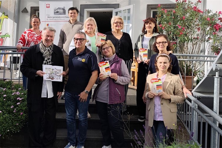 (v. l. n. r.) Susanne Breitbach, Dieter Klein, Simon Schmitten, Jürgen Nett, Teilnehmerinnen des Sprach-Cafés und Ehrenamtliche Iris Gabriel bei der Spendenübergabe der Bücher.