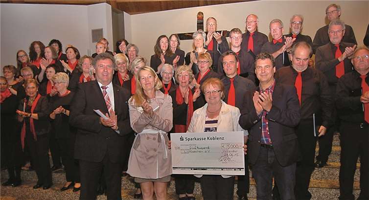 (v.l.) Sparkassenvorstand Ernst Josef Lehrer, die 2. Vorsitzende von Lichtzeichen e.V., Martina Sauer, die 1. Vorsitzende Maria Engler, Sparkassenchef Matthias Nester sowie im Hintergrund Mitglieder des Chors der Sparkasse Koblenz.privat