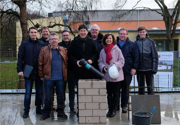 (v.l.n.r.): Die Architekten Reiner Braun und Christoph Schneider, Ortsvorsteher Manfred Keller, Joachim Datzert vom Schul- und Sportamt, Bürgermeister Michael Mang, Ortsvorsteher Frank Schaback, Günsel Hübner-Afacan vom Amt für Immobilienmanagement und Ralf und Sebastian Rösner vom VfL Wied versenken gemeinsam die Zeitkapsel.Stadt Neuwied